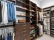 Organized walk-in closet with dark wood shelving, drawers, and hanging rods for clothes at 16407 Daysailor Trl, Lakewood Ranch, FL 34202