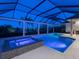 Night view of a screened-in pool with a jacuzzi and patio under a covered area at 16407 Daysailor Trl, Lakewood Ranch, FL 34202