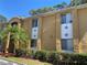 Exterior view of condo building with palm trees, hedges and parking spaces at 1721 Parakeet Way # 700, Sarasota, FL 34232