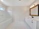 Well-lit bathroom featuring double sinks, a tub, and white tiled floors at 2407 Waterford Ct, Palmetto, FL 34221