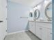Bathroom with double sinks, framed oval mirrors, white cabinets, tile floors and light blue walls at 2625 Terra Ceia Bay Blvd # 506, Palmetto, FL 34221