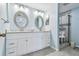 Bathroom with double sinks, white cabinets, framed oval mirrors, glass enclosed shower and light blue walls at 2625 Terra Ceia Bay Blvd # 506, Palmetto, FL 34221