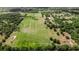 The aerial view shows a lush, green property with a pond and a mix of open fields and wooded areas at 28120 63Rd E Ave, Myakka City, FL 34251