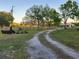 Winding gravel driveway leading to a countryside property, framed by mature trees and a split rail fence at 28120 63Rd E Ave, Myakka City, FL 34251