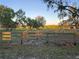 Picturesque fenced pasture with grazing animals beneath a canopy of mature trees, bathed in the warm glow of sunlight at 28120 63Rd E Ave, Myakka City, FL 34251