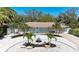 Charming one-story home features a circular driveway with decorative landscaping, an eye-catching turquoise door, and lush tropical trees at 3304 7Th Street W Ct, Palmetto, FL 34221
