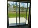 View of the backyard, as seen through sliding glass doors, overlooking green space and a white fence at 4656 Pleasant Ave, Palm Harbor, FL 34683
