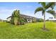 Expansive backyard with lush landscaping, tropical palm trees, and a screened-in patio with a stunning house at 4820 Coastal Days Ln, Bradenton, FL 34211