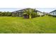 Lush green backyard featuring well-maintained lawn, tropical foliage, and screened-in patio with a beautiful home at 4820 Coastal Days Ln, Bradenton, FL 34211