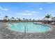 Large community pool with lounge chairs and palm trees under a sunny, partly cloudy sky at 4820 Coastal Days Ln, Bradenton, FL 34211