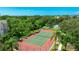 Aerial view of tennis court with lush landscaping and a clubhouse in the background at 5160 Northridge Rd # 206, Sarasota, FL 34238