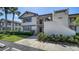 Condo exterior shows lush lawn, garden beds, covered main entry, and second story balcony at 5630 Golf Pointe Dr # 205, Sarasota, FL 34243