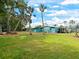 Large grassy backyard with palm trees and a blue house with white trim on a sunny day at 5910 Majestic Way, Palmetto, FL 34221