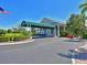 Welcoming clubhouse entrance featuring a covered drive, lush landscaping, and the American flag at 6821 Fairview Ter # 6821, Bradenton, FL 34203