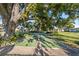 Outdoor shuffleboard court with lush green surroundings in a tranquil community setting, shaded by a large, mature tree at 7122 11Th W Ave, Bradenton, FL 34209