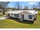 Charming single-story home with a metal roof, white exterior, blue awnings, and a well-manicured lawn at 7150 Richardson Rd, Sarasota, FL 34240