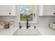 White farmhouse sink and faucet beneath a window overlooking backyard greenery at 7150 Richardson Rd, Sarasota, FL 34240
