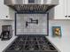 Close-up of a range with a decorative tile backsplash and stainless steel hood at 7150 Richardson Rd, Sarasota, FL 34240