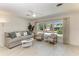 Cozy living room featuring a comfortable sofa, chairs, neutral paint, large windows, and tile floors at 105 Los Cedros Dr, Anna Maria, FL 34216