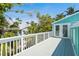 A deck with white railings is surrounded by palm trees and lush greenery at 111 Faubel St, Sarasota, FL 34242