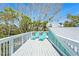 A bright deck with white railings is surrounded by palm trees and lush greenery at 111 Faubel St, Sarasota, FL 34242