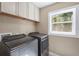 Bright laundry room equipped with a modern washer and dryer set and overhead cabinets at 111 Faubel St, Sarasota, FL 34242