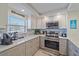 Kitchen featuring modern stainless appliances, granite countertops, custom cabinets, and mosaic backsplash at 1250 N Portofino Dr # 203, Sarasota, FL 34242