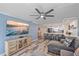Open concept living room boasts a large tv, ceiling fan, and open access to the kitchen at 1250 N Portofino Dr # 203, Sarasota, FL 34242