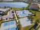 Aerial view showcasing community tennis courts, basketball court, pool, and a picturesque lake at 18013 Polo Trl, Bradenton, FL 34211