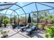 A relaxing outdoor patio with a seating area, fire pit, lounge chairs, and greenery, all enclosed by a screened lanai at 18013 Polo Trl, Bradenton, FL 34211