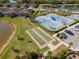 Aerial view of tennis and bocce ball courts, with scenic pond views and community landscaping at 18013 Polo Trl, Bradenton, FL 34211