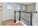Stylish staircase with wood floors, white railings and black banisters, illuminated by natural light from nearby windows at 18013 Polo Trl, Bradenton, FL 34211