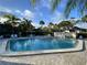 Community pool surrounded by lush landscaping, lounge chairs, and clear blue sky at 3500 El Conquistador Pkwy # 357, Bradenton, FL 34210