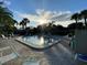 Community pool with brick paver deck, surrounded by palm trees, lounge chairs, and privacy fencing at 3500 El Conquistador Pkwy # 357, Bradenton, FL 34210