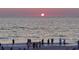 Stunning sunset over the ocean with silhouetted people enjoying the view from the sandy beach at 3708 Plumosa Ter, Bradenton, FL 34210