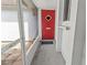 Close-up of the bright red front door with screen door access, shelf, and security features at 3908 Panola Ln # 193, Sarasota, FL 34232