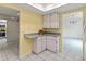 Galley kitchen with white cabinets, tile floors, and view to the dining and additional kitchen area at 3908 Panola Ln # 193, Sarasota, FL 34232