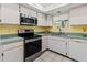 Galley kitchen featuring stainless steel microwave and stove along with white cabinets and sink at 3908 Panola Ln # 193, Sarasota, FL 34232