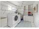 Well-equipped laundry room with washer, dryer, utility sink, shelving, cabinets, and tiled floor at 3908 Panola Ln # 193, Sarasota, FL 34232