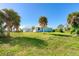 Large, grassy backyard with palms and a view of the home's rear exterior at 3910 Cape Haze Dr, Rotonda West, FL 33947