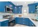 Well-lit kitchen showcasing blue cabinetry, stainless steel appliances and white countertops at 3910 Cape Haze Dr, Rotonda West, FL 33947