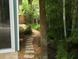 Backyard stone pathway leading through lush tropical landscaping, with a glimpse of the home's exterior at 402 71St St, Holmes Beach, FL 34217