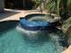 A close-up of a lovely waterfall feature flowing into an in-ground pool and spa at 402 71St St, Holmes Beach, FL 34217