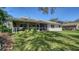 Exterior view of the home with a screened lanai and lush backyard with mature trees offering shade at 4420 Oak View Dr, Sarasota, FL 34232