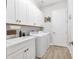 Well-lit laundry room with modern washer/dryer, ample white cabinetry, and a convenient utility sink at 510 16Th E Ave, Palmetto, FL 34221