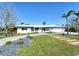 Beautiful one-story home with lush front yard, walkway and driveway, palm trees, and modern architectural style at 537 Gunwale Ln, Longboat Key, FL 34228