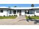 Charming single-story home featuring a modern white exterior, complemented by lush landscaping and a brick walkway to the front door at 537 Gunwale Ln, Longboat Key, FL 34228