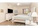 Well-lit bedroom with a modern TV, white dresser, comfortable bed, side table and decorative details at 615 Riviera Dunes Way # 208, Palmetto, FL 34221