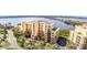 Beautiful multi-story condo building with barrel tile roof, tropical landscaping, and water views at 615 Riviera Dunes Way # 208, Palmetto, FL 34221