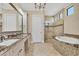 Bathroom featuring double sinks with marble countertops, a soaking tub, and a walk-in shower at 6211 Legends Blvd, Bradenton, FL 34210